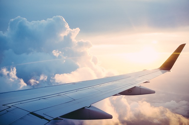 Wing of an airplane against clouds and sunrise